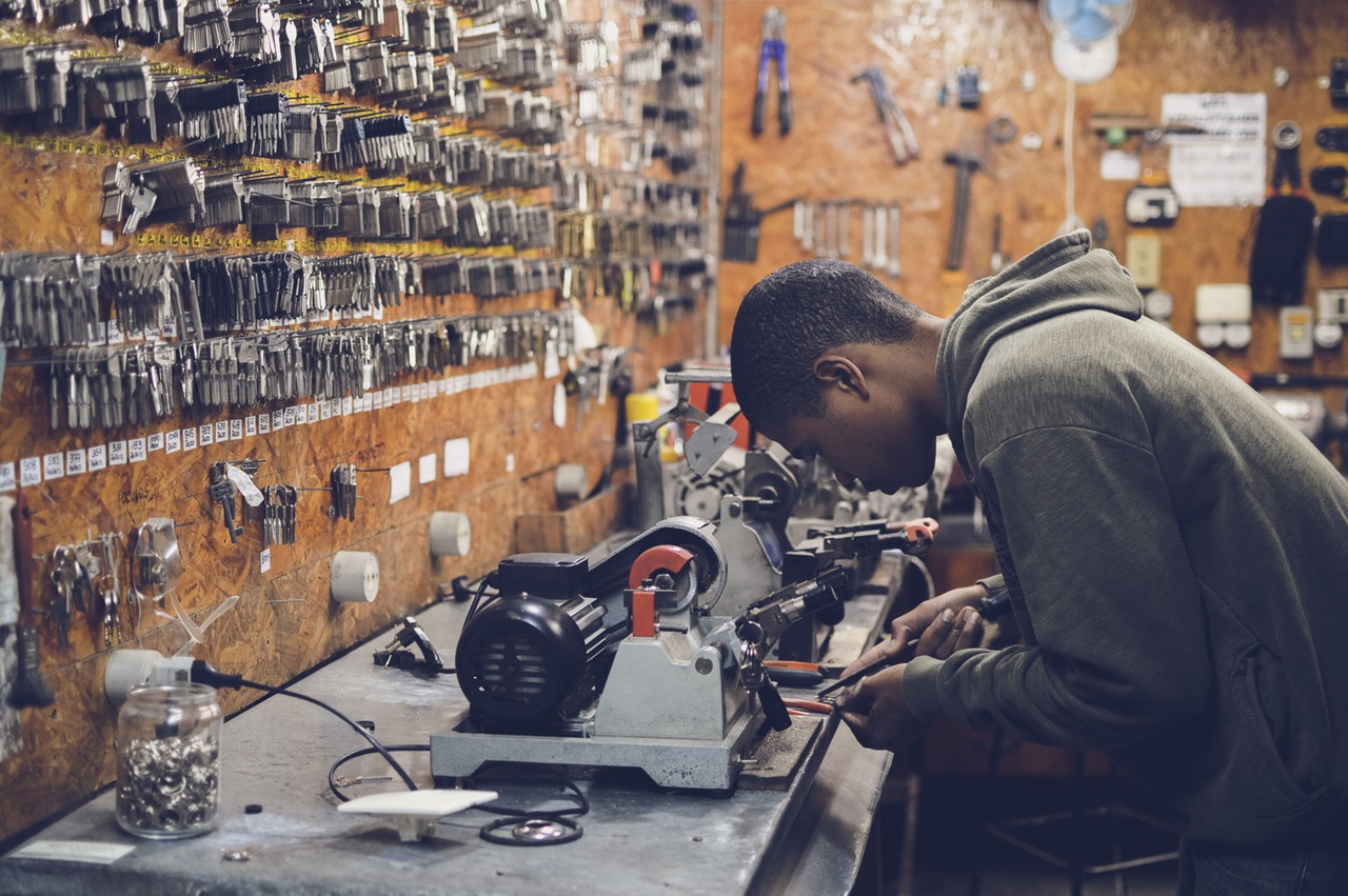 Locksmith in Workshop Makes New Key. Professional Making Key in